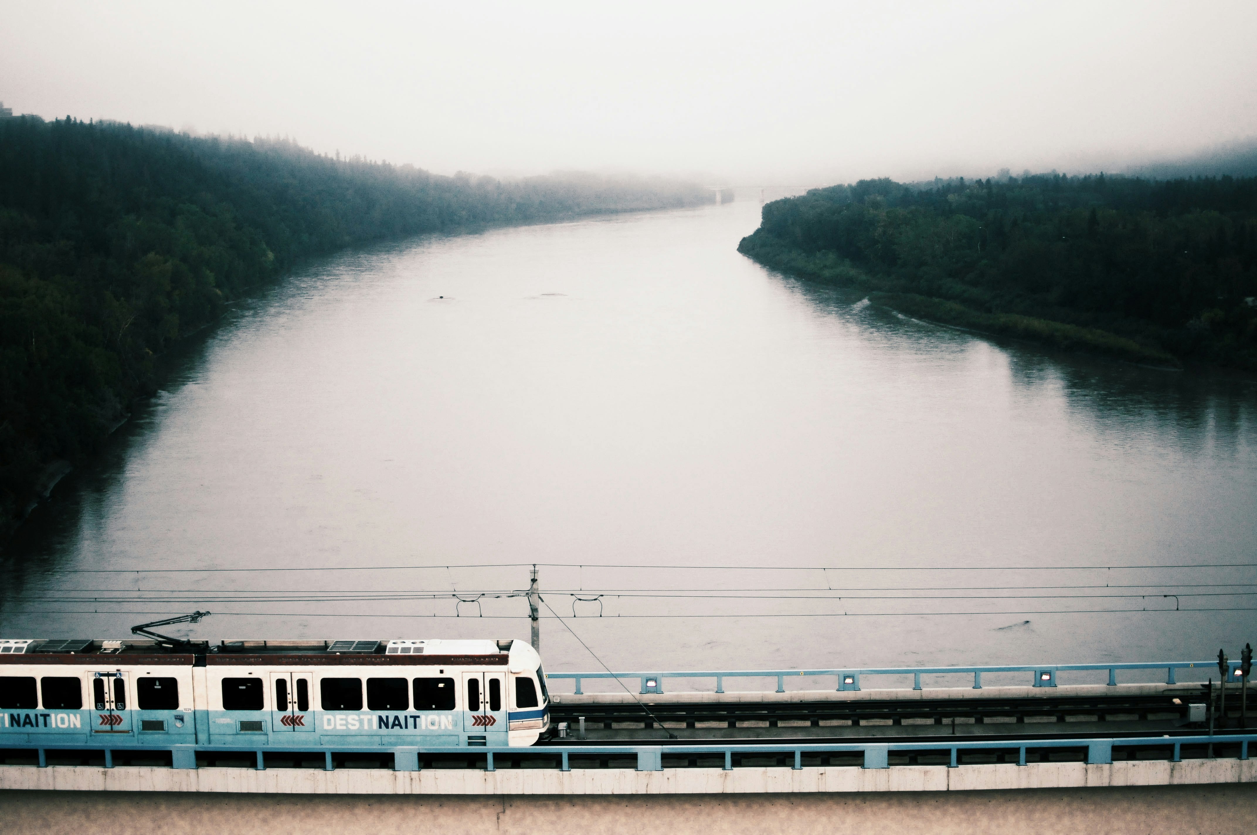 white train on bridge over river during daytime